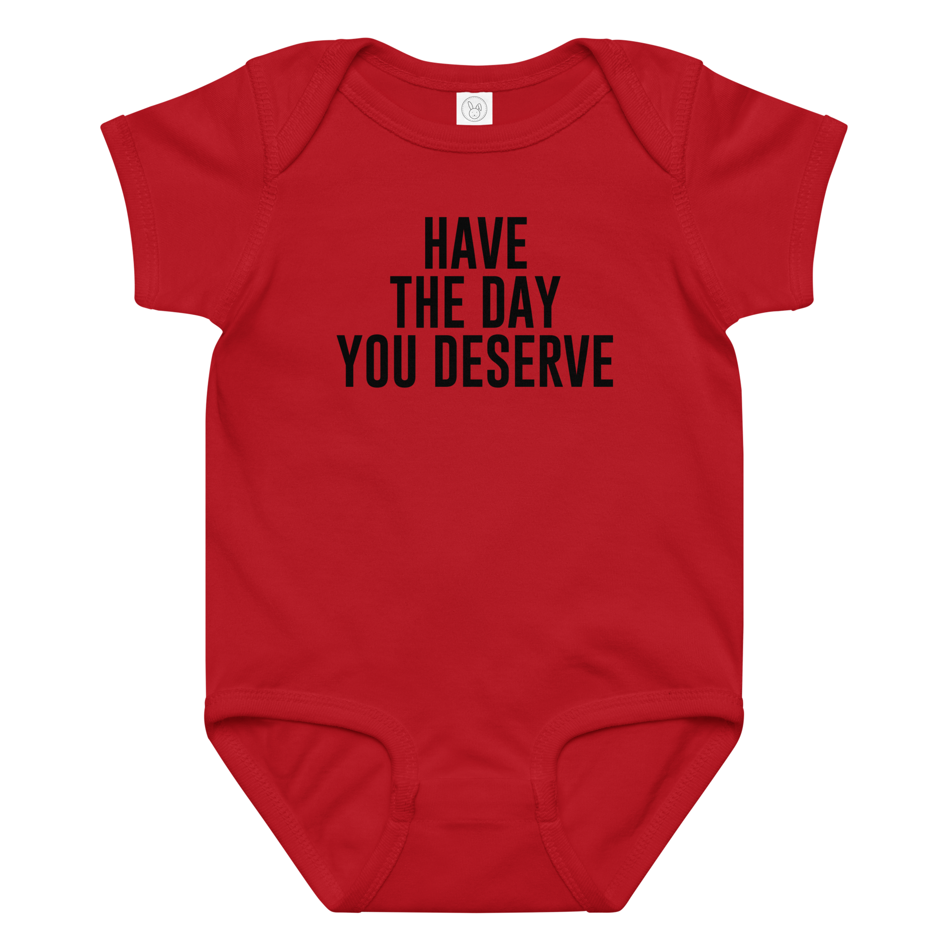 "Have the day you deserve" printed on a red baby jersey bodysuit laying on a flat surface amongst other clothes