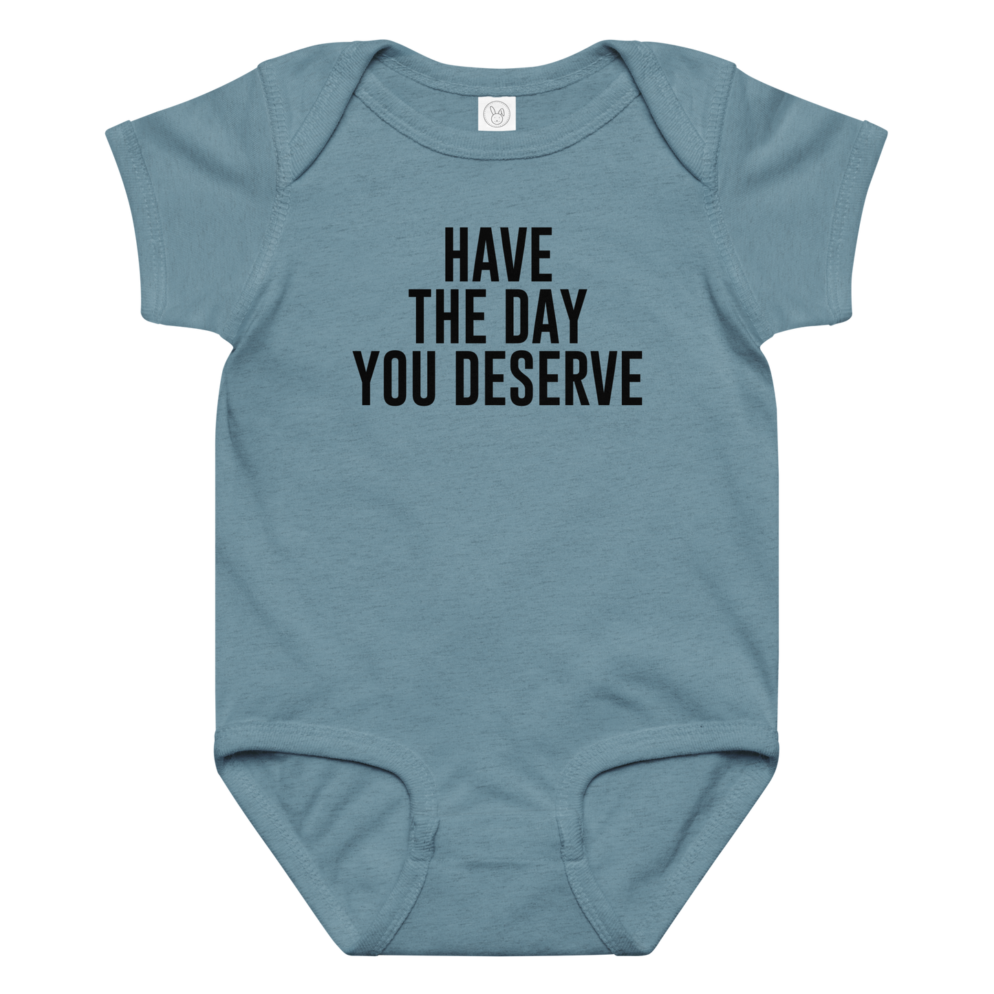 "Have the day you deserve" printed on a vintage indigo baby jersey bodysuit laying on a flat surface amongst other clothes