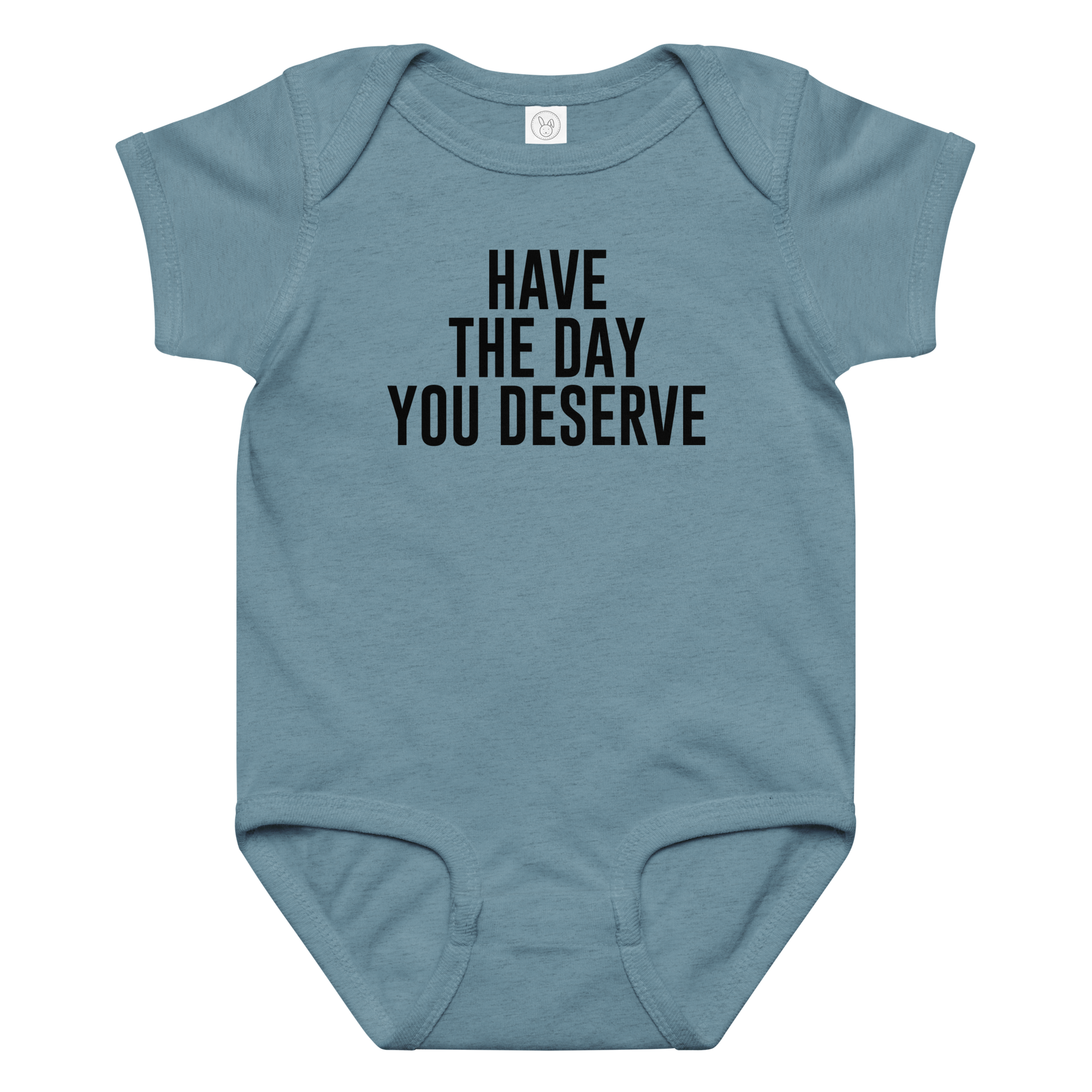 "Have the day you deserve" printed on a vintage indigo baby jersey bodysuit laying on a flat surface amongst other clothes