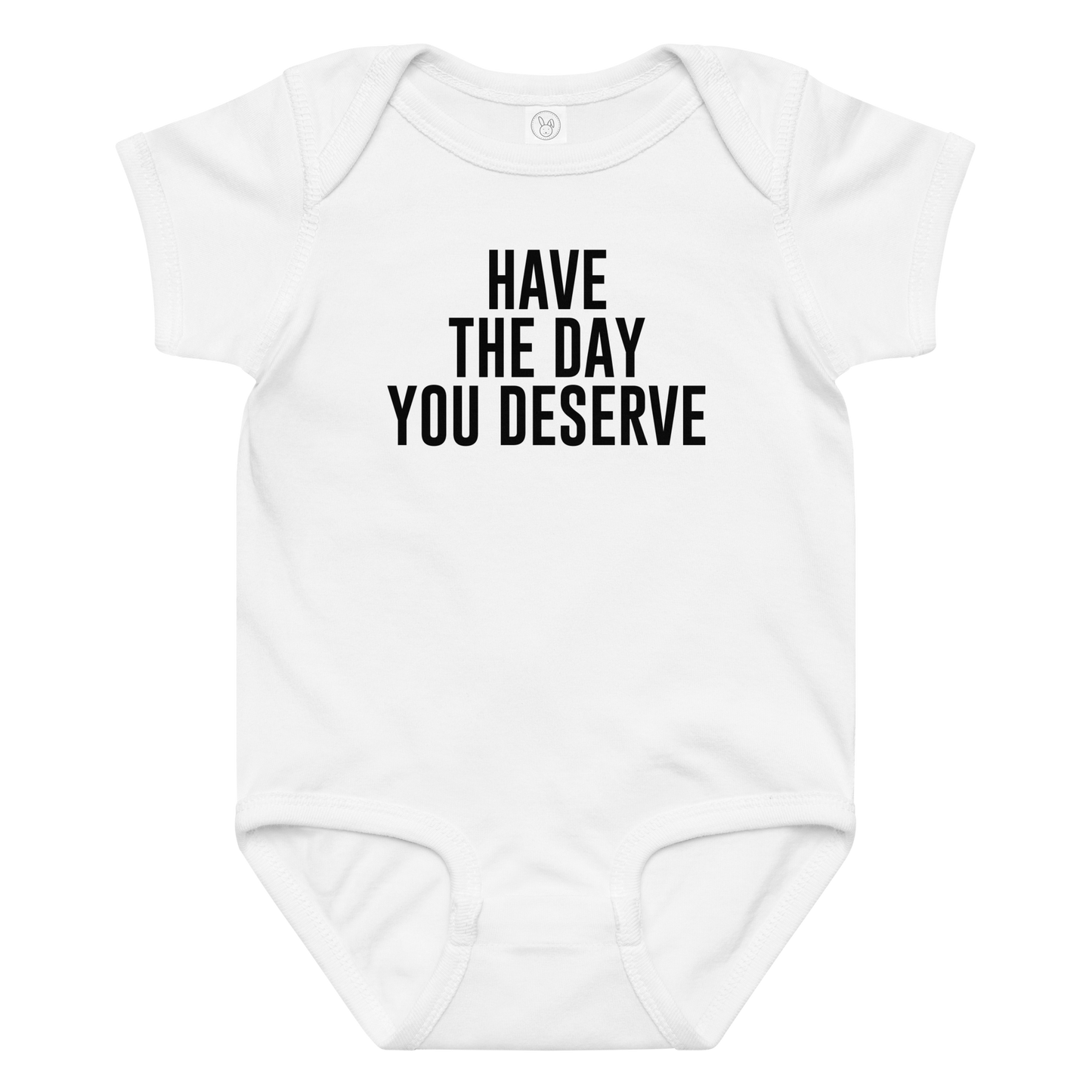 "Have the day you deserve" printed on a white baby jersey bodysuit laying on a flat surface amongst other clothes