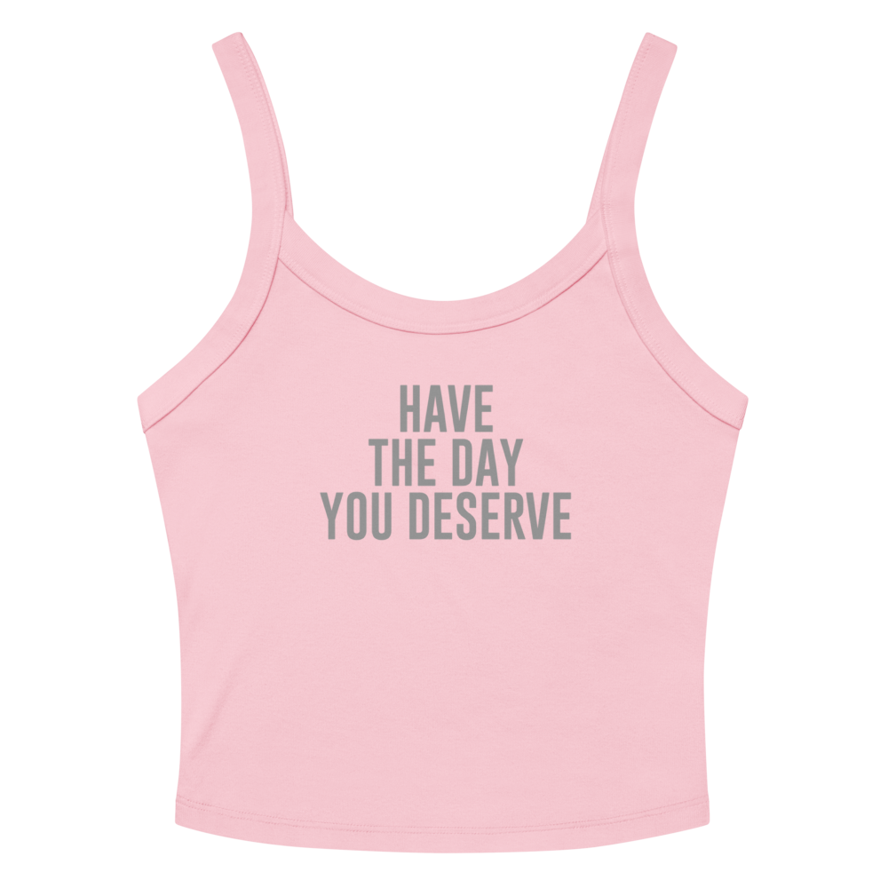 "Have the day you deserve" printed on a solid pink blend women's micro-rib tanktop laying on a flat surface amongst sunglasses and shorts