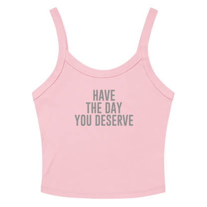 "Have the day you deserve" printed on a solid pink blend women's micro-rib tanktop laying on a flat surface amongst sunglasses and shorts