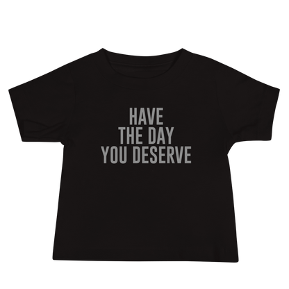 "Have the day you deserve" printed on a black baby jersey short sleeve tee laying on a flat surface