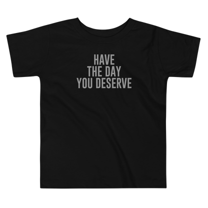 "Have the day you deserve" printed on a black toddler short sleeve tee laying on a flat surface