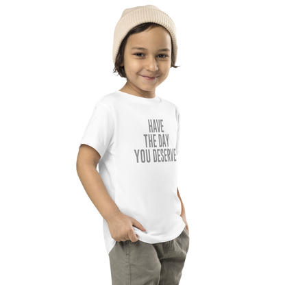"Have the day you deserve" printed on a white toddler short sleeve tee worn by a male who is also wearing a knit cap