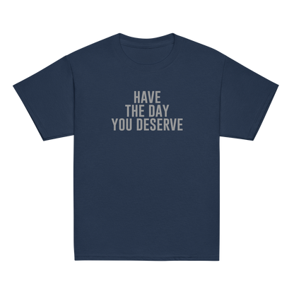 "Have the day you deserve" printed on a navy youth classic tee laying on a flat surface