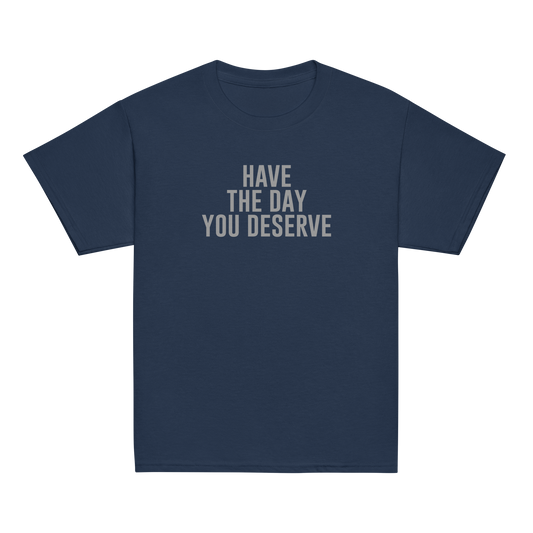 "Have the day you deserve" printed on a navy youth classic tee laying on a flat surface