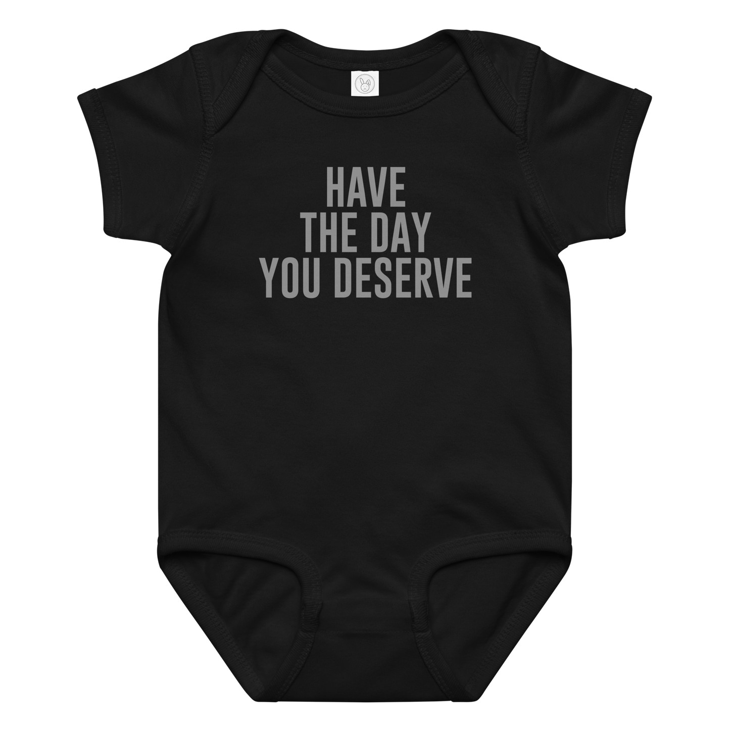 "Have the day you deserve" printed on a black baby jersey bodysuit laying on a flat surface amongst other clothes