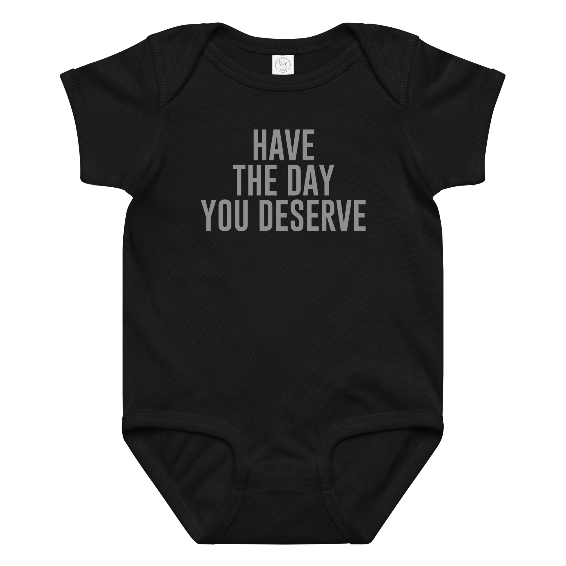"Have the day you deserve" printed on a black baby jersey bodysuit laying on a flat surface amongst other clothes