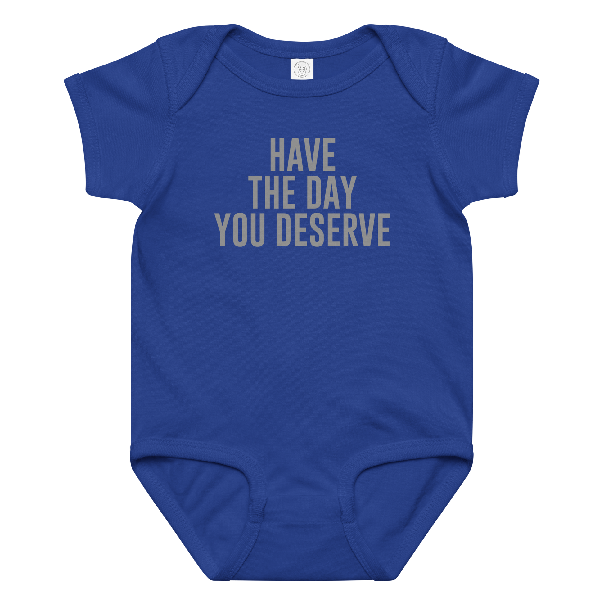 "Have the day you deserve" printed on a royal baby jersey bodysuit laying on a flat surface amongst other clothes