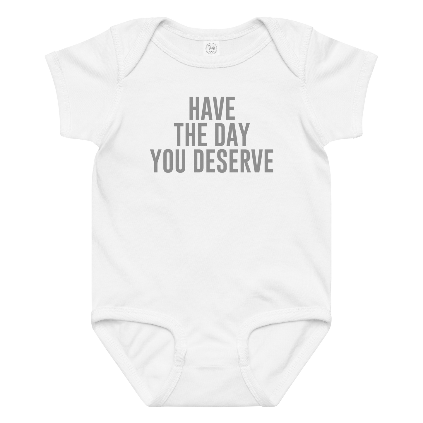 "Have the day you deserve" printed on a white baby jersey bodysuit laying on a flat surface amongst other clothes