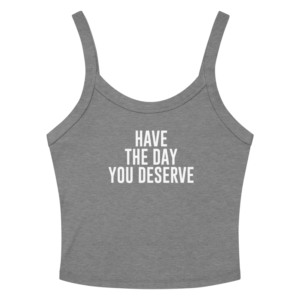 "Have the day you deserve" printed on a athletic heather women's micro-rib tanktop laying on a flat surface amongst sunglasses and shorts