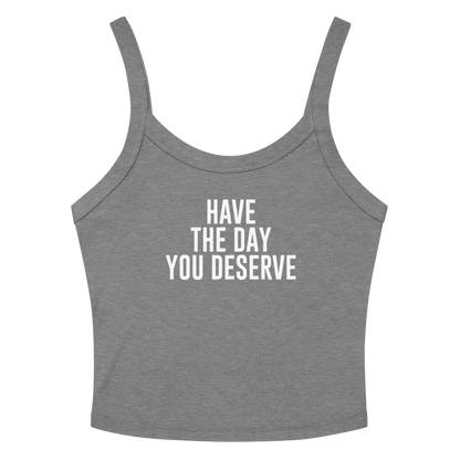 "Have the day you deserve" printed on a athletic heather women's micro-rib tanktop laying on a flat surface amongst sunglasses and shorts