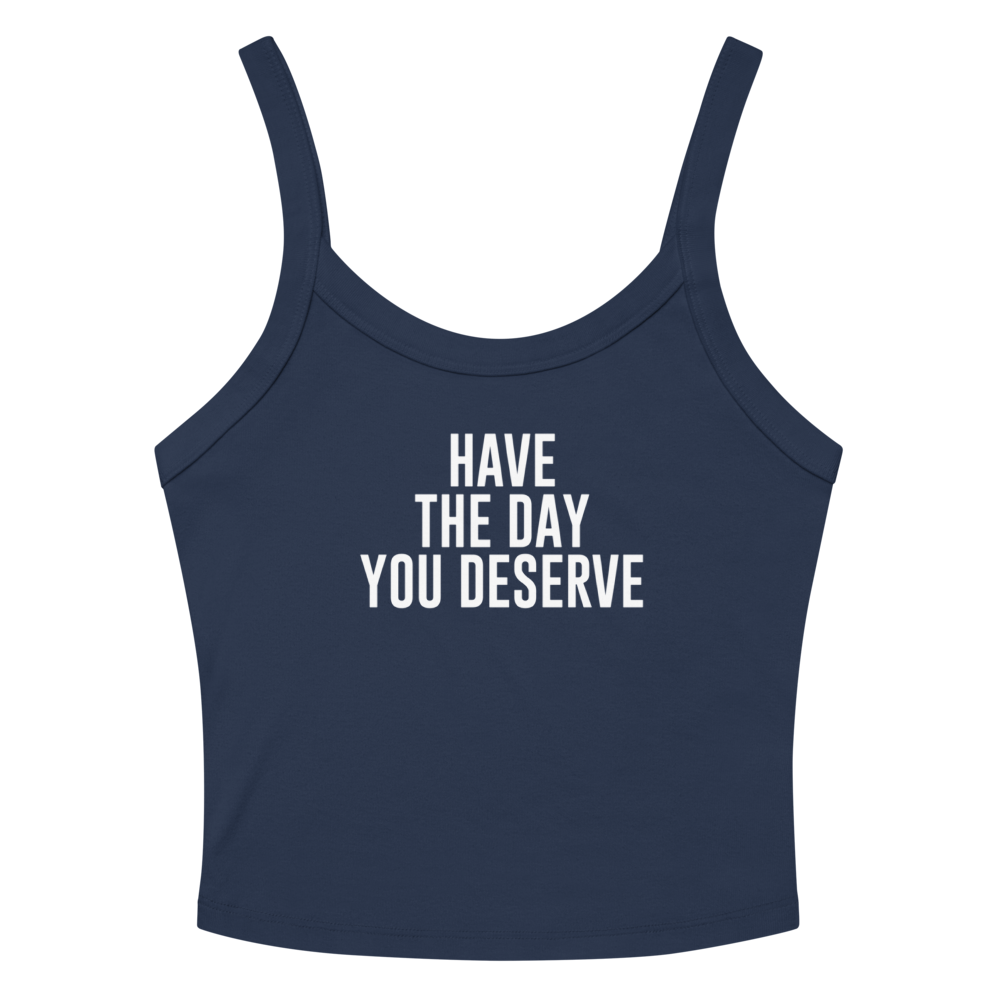 "Have the day you deserve" printed on a solid navy blend women's micro-rib tanktop laying on a flat surface amongst sunglasses and shorts