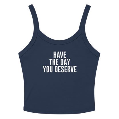 "Have the day you deserve" printed on a solid navy blend women's micro-rib tanktop laying on a flat surface amongst sunglasses and shorts