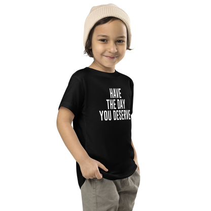 "Have the day you deserve" printed on a black toddler short sleeve tee worn by a male who is also wearing a knit cap