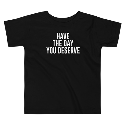 "Have the day you deserve" printed on a black toddler short sleeve tee laying on a flat surface
