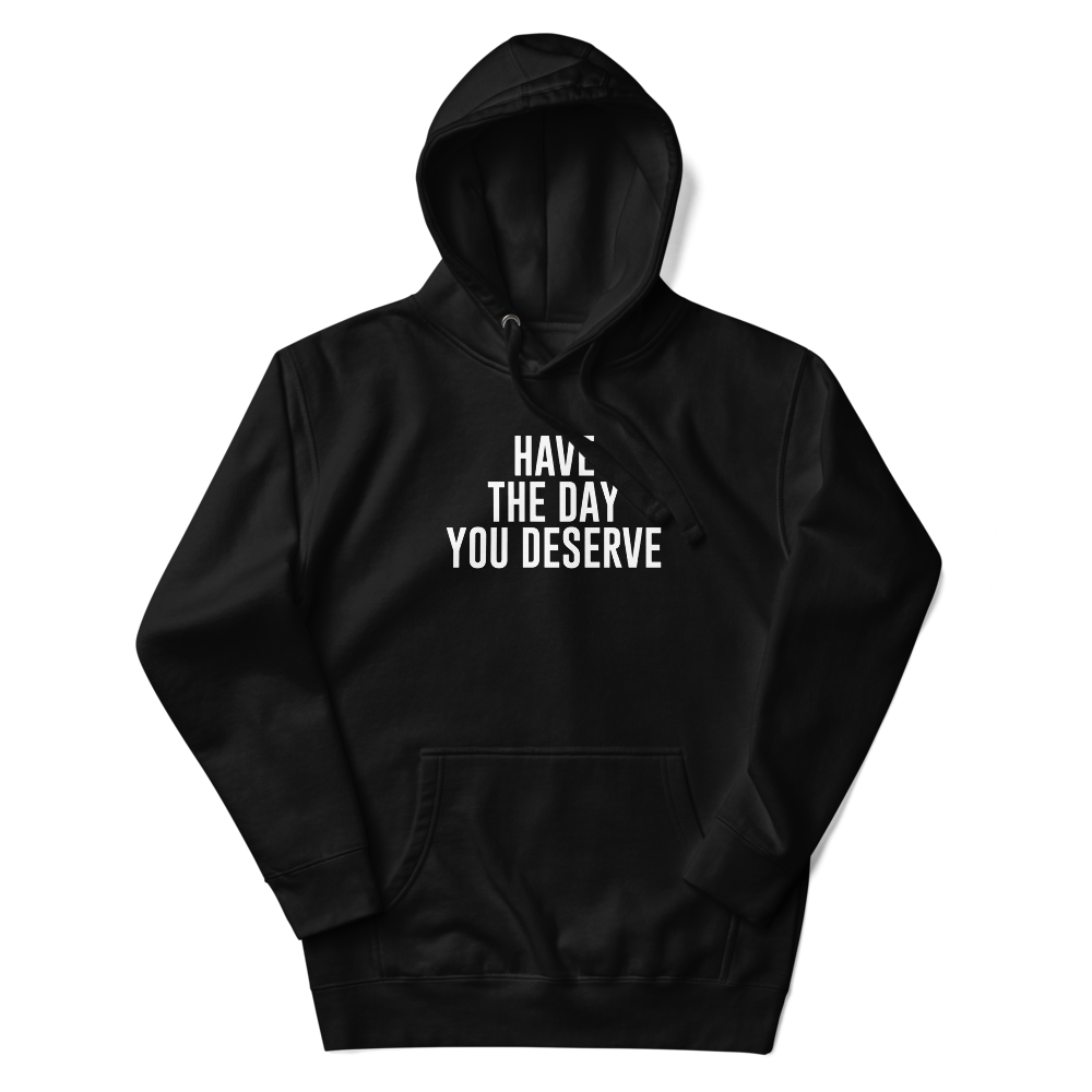 "Have the day you deserve" printed on a black unisex hoodie laying on a flat surface with the hood up