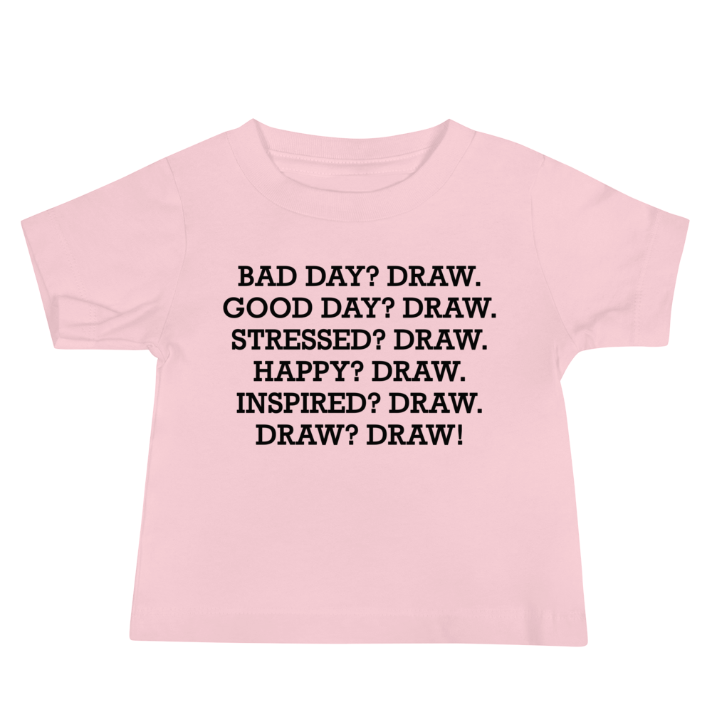 "Bad Day? Draw. Good Day? Draw. Stressed? Draw. Happy? Draw. Inspired? Draw. Draw? Draw!" printed on a pink baby jersey short sleeve tee laying on a flat surface