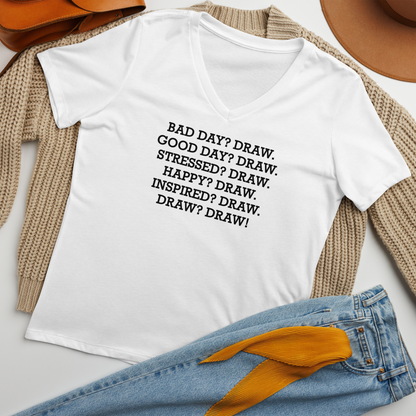 "Bad Day? Draw. Good Day? Draw. Stressed? Draw. Happy? Draw. Inspired? Draw. Draw? Draw!" printed on a solid white blend women's relaxed v-neck t-shirt laying on a flat surface amongst other clothes