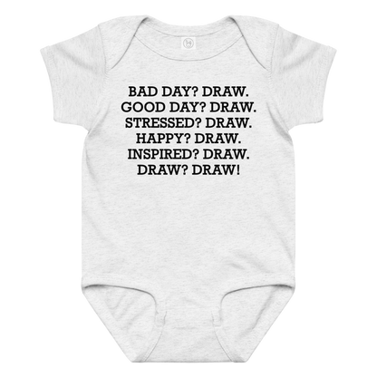 "Bad Day? Draw. Good Day? Draw. Stressed? Draw. Happy? Draw. Inspired? Draw. Draw? Draw!" printed on a ash baby jersey bodysuit laying on a flat surface amongst other clothes