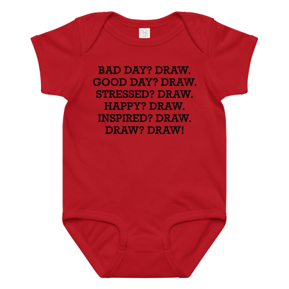 "Bad Day? Draw. Good Day? Draw. Stressed? Draw. Happy? Draw. Inspired? Draw. Draw? Draw!" printed on a red baby jersey bodysuit laying on a flat surface amongst other clothes