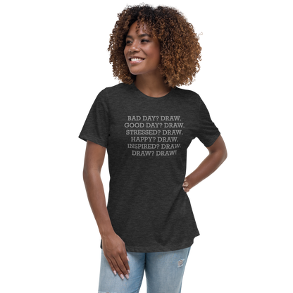 "Bad Day? Draw. Good Day? Draw. Stressed? Draw. Happy? Draw. Inspired? Draw. Draw? Draw!" printed on a dark grey heather women's relaxed t-shirt worn by a female