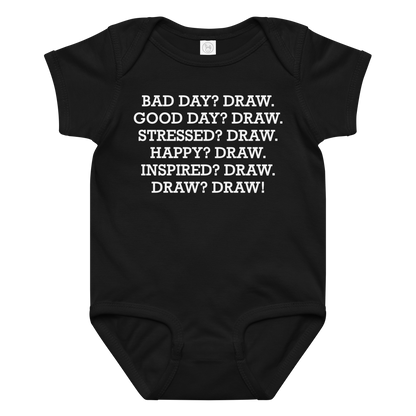"Bad Day? Draw. Good Day? Draw. Stressed? Draw. Happy? Draw. Inspired? Draw. Draw? Draw!" printed on a black baby jersey bodysuit laying on a flat surface amongst other clothes