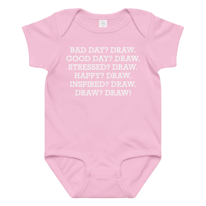 "Bad Day? Draw. Good Day? Draw. Stressed? Draw. Happy? Draw. Inspired? Draw. Draw? Draw!" printed on a pink baby jersey bodysuit laying on a flat surface amongst other clothes