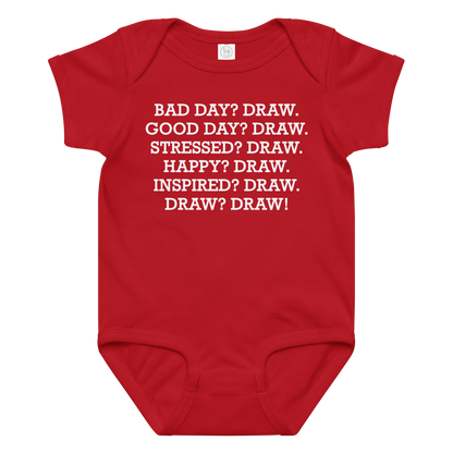 "Bad Day? Draw. Good Day? Draw. Stressed? Draw. Happy? Draw. Inspired? Draw. Draw? Draw!" printed on a red baby jersey bodysuit laying on a flat surface amongst other clothes