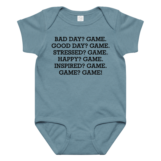 "Bad Day? Game. Good Day? Game. Stressed? Game. Happy? Game. Inspired? Game. Game? Game!" printed on a vintage indigo baby jersey bodysuit laying on a flat surface amongst other clothes