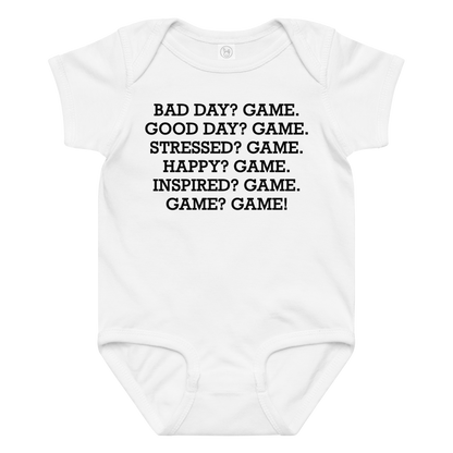 "Bad Day? Game. Good Day? Game. Stressed? Game. Happy? Game. Inspired? Game. Game? Game!" printed on a white baby jersey bodysuit laying on a flat surface amongst other clothes