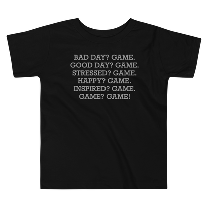 "Bad Day? Game. Good Day? Game. Stressed? Game. Happy? Game. Inspired? Game. Game? Game!" printed on a black toddler short sleeve tee laying on a flat surface