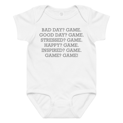 "Bad Day? Game. Good Day? Game. Stressed? Game. Happy? Game. Inspired? Game. Game? Game!" printed on a white baby jersey bodysuit laying on a flat surface amongst other clothes