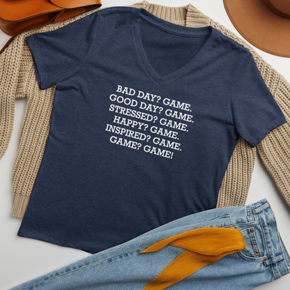 "Bad Day? Game. Good Day? Game. Stressed? Game. Happy? Game. Inspired? Game. Game? Game!" printed on a heather navy women's relaxed v-neck t-shirt laying on a flat surface amongst other clothes