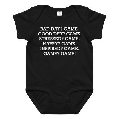 "Bad Day? Game. Good Day? Game. Stressed? Game. Happy? Game. Inspired? Game. Game? Game!" printed on a black baby jersey bodysuit laying on a flat surface amongst other clothes