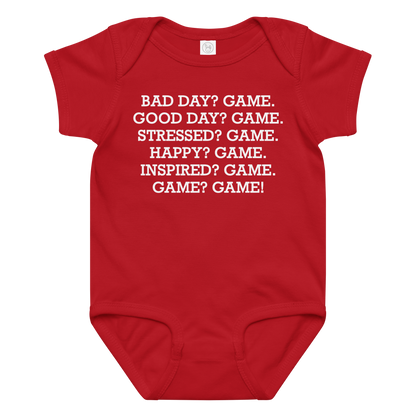 "Bad Day? Game. Good Day? Game. Stressed? Game. Happy? Game. Inspired? Game. Game? Game!" printed on a red baby jersey bodysuit laying on a flat surface amongst other clothes