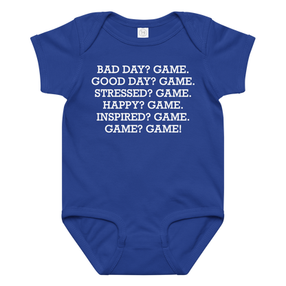 "Bad Day? Game. Good Day? Game. Stressed? Game. Happy? Game. Inspired? Game. Game? Game!" printed on a royal baby jersey bodysuit laying on a flat surface amongst other clothes