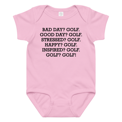 "Bad Day? Golf. Good Day? Golf. Stressed? Golf. Happy? Golf. Inspired? Golf. Golf? Golf!" printed on a pink baby jersey bodysuit laying on a flat surface amongst other clothes