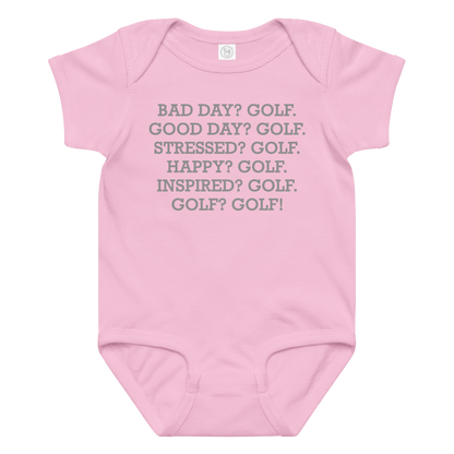 "Bad Day? Golf. Good Day? Golf. Stressed? Golf. Happy? Golf. Inspired? Golf. Golf? Golf!" printed on a pink baby jersey bodysuit laying on a flat surface amongst other clothes