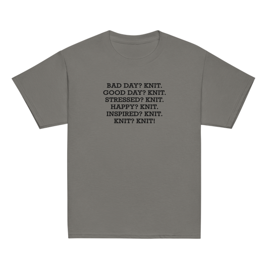 "Bad Day? Knit. Good Day? Knit. Stressed? Knit. Happy? Knit. Inspired? Knit. Knit? Knit!" printed on a charcoal youth classic tee laying on a flat surface