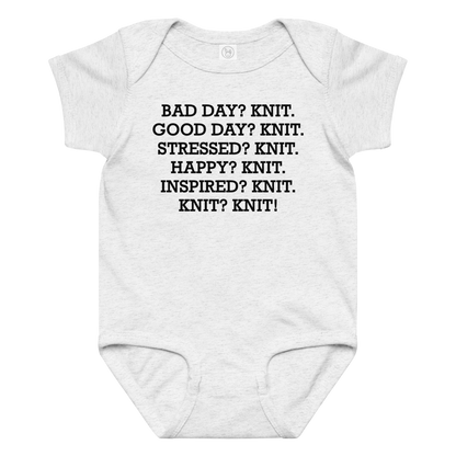 "Bad Day? Knit. Good Day? Knit. Stressed? Knit. Happy? Knit. Inspired? Knit. Knit? Knit!" printed on a ash baby jersey bodysuit laying on a flat surface amongst other clothes