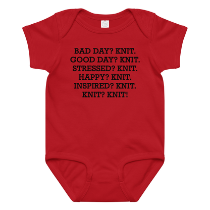 "Bad Day? Knit. Good Day? Knit. Stressed? Knit. Happy? Knit. Inspired? Knit. Knit? Knit!" printed on a red baby jersey bodysuit laying on a flat surface amongst other clothes