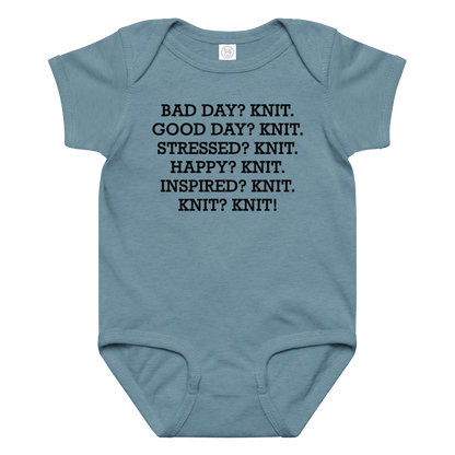 "Bad Day? Knit. Good Day? Knit. Stressed? Knit. Happy? Knit. Inspired? Knit. Knit? Knit!" printed on a vintage indigo baby jersey bodysuit laying on a flat surface amongst other clothes