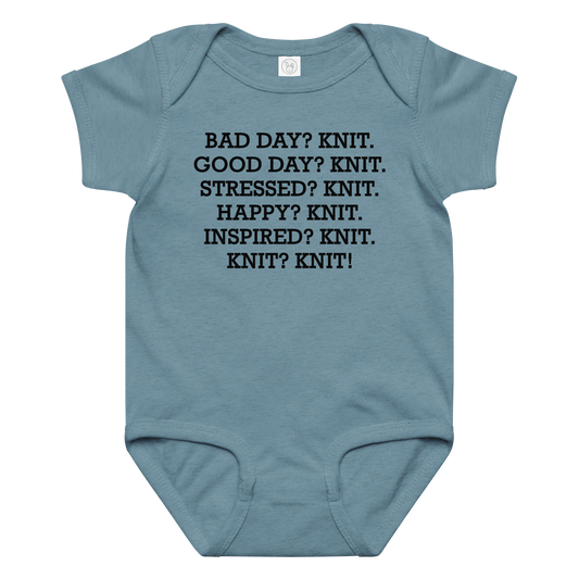 "Bad Day? Knit. Good Day? Knit. Stressed? Knit. Happy? Knit. Inspired? Knit. Knit? Knit!" printed on a vintage indigo baby jersey bodysuit laying on a flat surface amongst other clothes