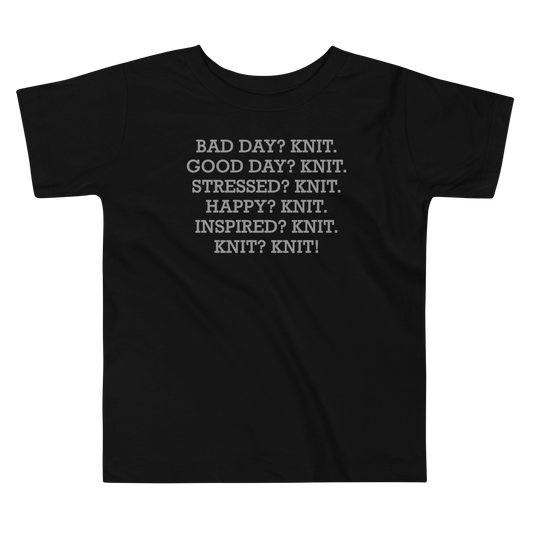 "Bad Day? Knit. Good Day? Knit. Stressed? Knit. Happy? Knit. Inspired? Knit. Knit? Knit!" printed on a black toddler short sleeve tee laying on a flat surface