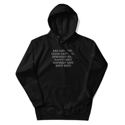 "Bad Day? Knit. Good Day? Knit. Stressed? Knit. Happy? Knit. Inspired? Knit. Knit? Knit!" printed on a black unisex hoodie laying on a flat surface with the hood up