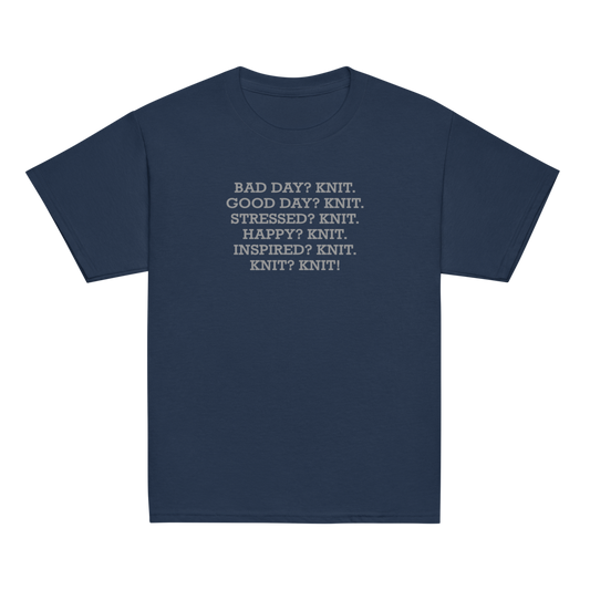 "Bad Day? Knit. Good Day? Knit. Stressed? Knit. Happy? Knit. Inspired? Knit. Knit? Knit!" printed on a navy youth classic tee laying on a flat surface