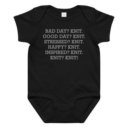 "Bad Day? Knit. Good Day? Knit. Stressed? Knit. Happy? Knit. Inspired? Knit. Knit? Knit!" printed on a black baby jersey bodysuit laying on a flat surface amongst other clothes