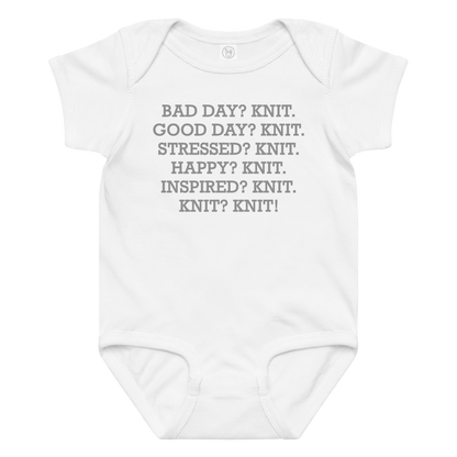 "Bad Day? Knit. Good Day? Knit. Stressed? Knit. Happy? Knit. Inspired? Knit. Knit? Knit!" printed on a white baby jersey bodysuit laying on a flat surface amongst other clothes